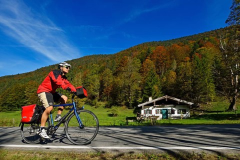 Tourist on a bicycle cycling on front of a hut