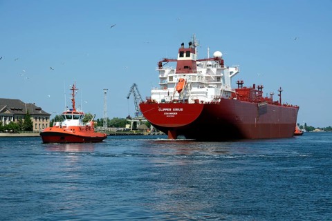 A cargo ship is towed from the Gdansk shipyard by a tug boat