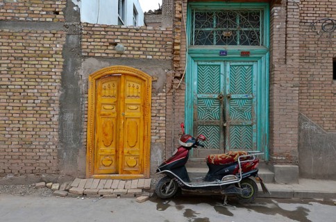 Motor scooter in front of old Uighur Muslim doorframes in new homes