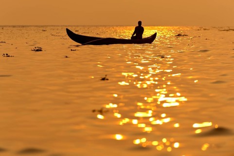 Fisherman in his boat at sunrise