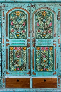 Ornately carved flowers in a turquoise cabinet door