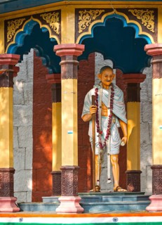 Representation of Mahatma Gandhi with walking stick in a small pavilion on the temple wall