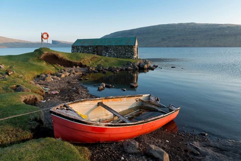 Red boat in front of a boat house on Lake Sorvagsvatn or Leitisvatn