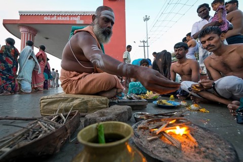 Hindu priest with pilgrims performing a fire ritual at the Ghat Agni Theertham