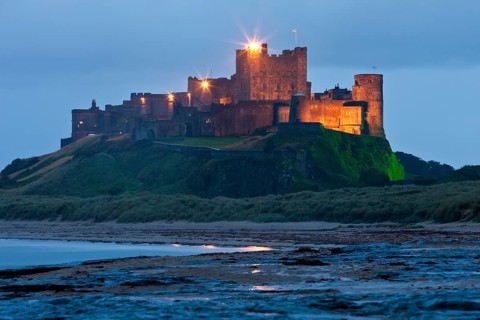 Bamburgh Castle illuminated at dusk