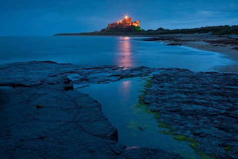 Bamburgh Castle illuminated at dusk