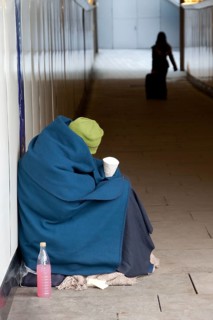 Homeless person wrapped in a blanket sitting in an underpass