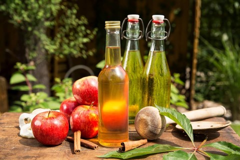 Apples with apple cider vinegar and apple juice on a wooden box in the garden