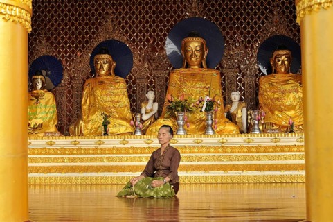 Woman meditating in front of Buddha statues