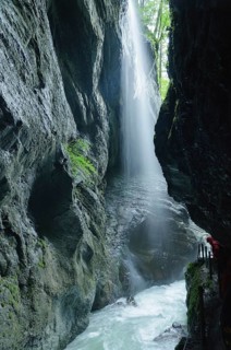 Hiker observing a waterfall in the Partnachklamm gorge