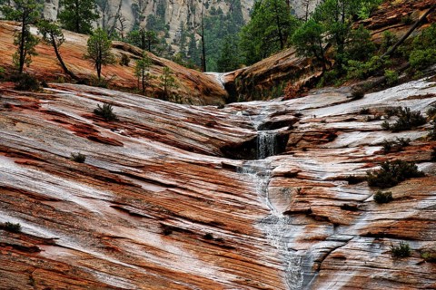 Water draining off over red Navajo sandstone rocks after a rainstorm near Canyon Overlook