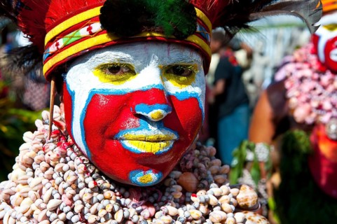 Woman in a colourfully decorated costume with face paint at the traditional sing-sing gathering