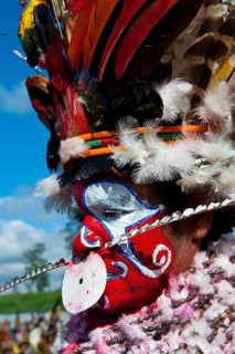 Woman in a colourfully decorated costume with face paint at the traditional sing-sing gathering