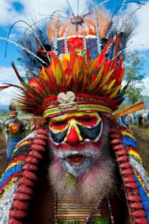 Man in a colourfully decorated costume with face paint at the traditional sing-sing gathering
