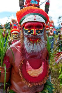 Man in a colourfully decorated costume with face paint at the traditional sing-sing gathering