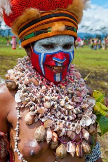 Woman in a colourfully decorated costume with face paint at the traditional sing-sing gathering