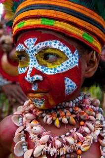 Member of a tribe in a colourfully decorated costume with face paint at the traditional sing-sing gathering
