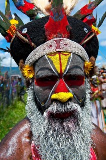 Man in a colourfully decorated costume with face paint at the traditional sing-sing gathering