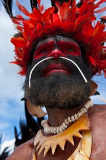 Man in a colourfully decorated costume with face paint at the traditional sing-sing gathering