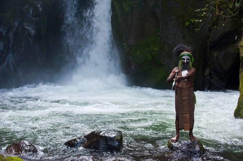 Decorated and painted tribal chief standing in front of a waterfall in the Highlands