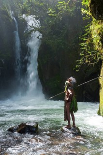 Decorated and painted tribal chief standing in front of a waterfall in the Highlands