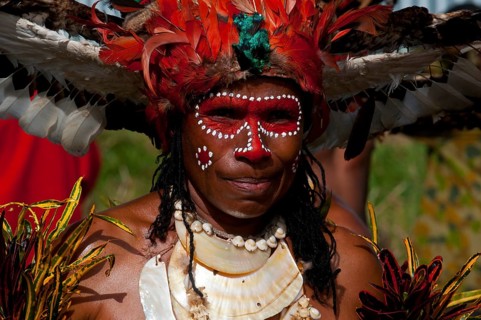 Member of a tribe in a colourfully decorated costume with face paint at the traditional sing-sing gathering
