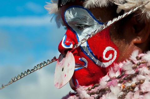 Member of a tribe in a colourfully decorated costume with face paint at the traditional sing-sing gathering
