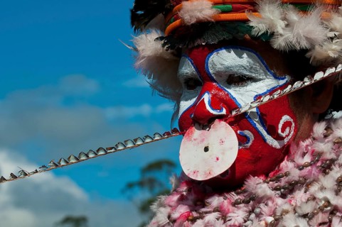 Member of a tribe in a colourfully decorated costume with face paint at the traditional sing-sing gathering