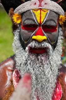 Member of a tribe in a colourfully decorated costume with face paint at the traditional sing-sing gathering
