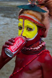 Colourfully decorated and painted boy drinking from a Coke can during the traditional Sing Sing in the highlands