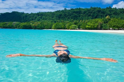 Woman floating in the water off Champagne Beach