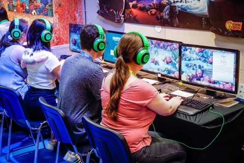 Visitors playing a computer game in front of screens
