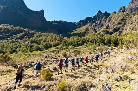 Hikers walk in single file up a slope of Col du Taibit