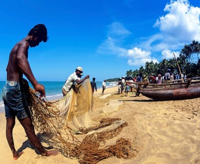 Fishermen repairing a fishing net on the beach