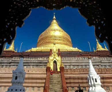 Monk on the stairs of Shwezigon Pagoda with its golden chedi