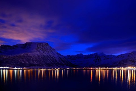 Reflection of lights in the fjord with mountains the blue hour