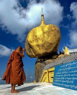 Buddhist Monk praying in front of the Golden Rock or Kyaiktiyo Pagoda