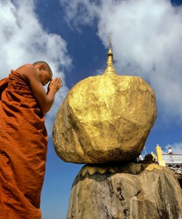 Buddhist Monk praying in front of the Golden Rock or Kyaiktiyo Pagoda
