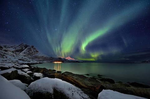 Aurora over fjord with snowy mountains