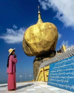 Woman praying in front of the Golden Rock or Kyaiktiyo Pagoda