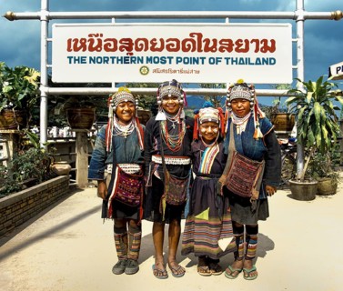 Akha hill tribe girls wearing traditional costumes and headdresses standing at the northernmost point of Thailand
