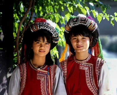 Two Lisu girls wearing colourful headdresses and the traditional costume of the mountain people