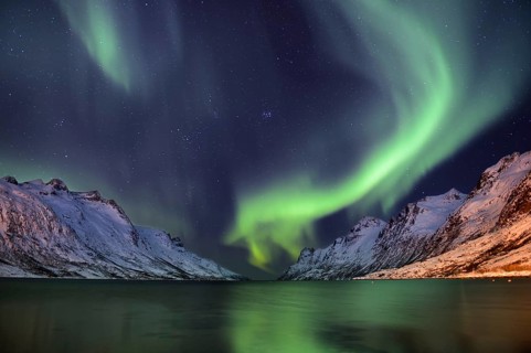 Aurora over a fjord with snow-covered mountains