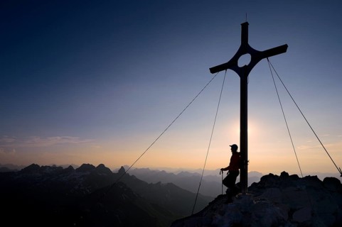 Mountaineer at the summit cross on Grosser Krottenkopf Mountain at dusk
