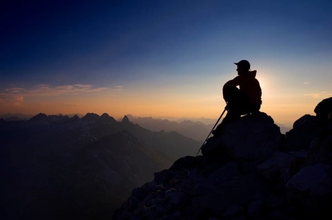Mountaineer sitting on a rock on Grosser Krottenkopf Mountain at dusk