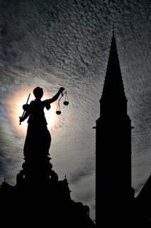 Justitia statue in front of the silhouette of the Old St. Nicholas Church
