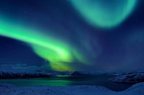 Northern Lights over fjord in winter landscape