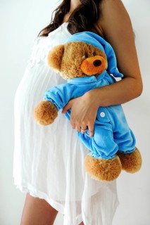 Woman with a pregnant belly holding a teddy bear
