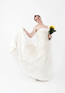 Man wearing a wedding dress and holding a bridal bouquet