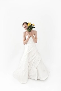 Man wearing a wedding dress and holding a bridal bouquet